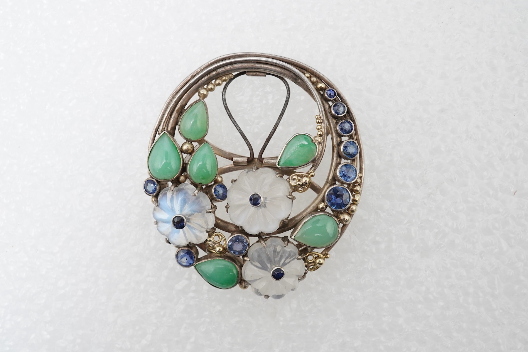Attributed to Dorrie Nossiter (1893-1977), an Arts & Crafts moonstone, sapphire and jadeite scarf clip, 1920s